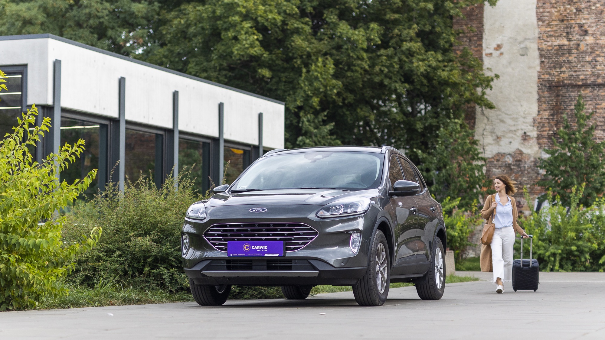 Carwiz Ford Kuga z kobietą podchodzącą z walizką — scena arrival